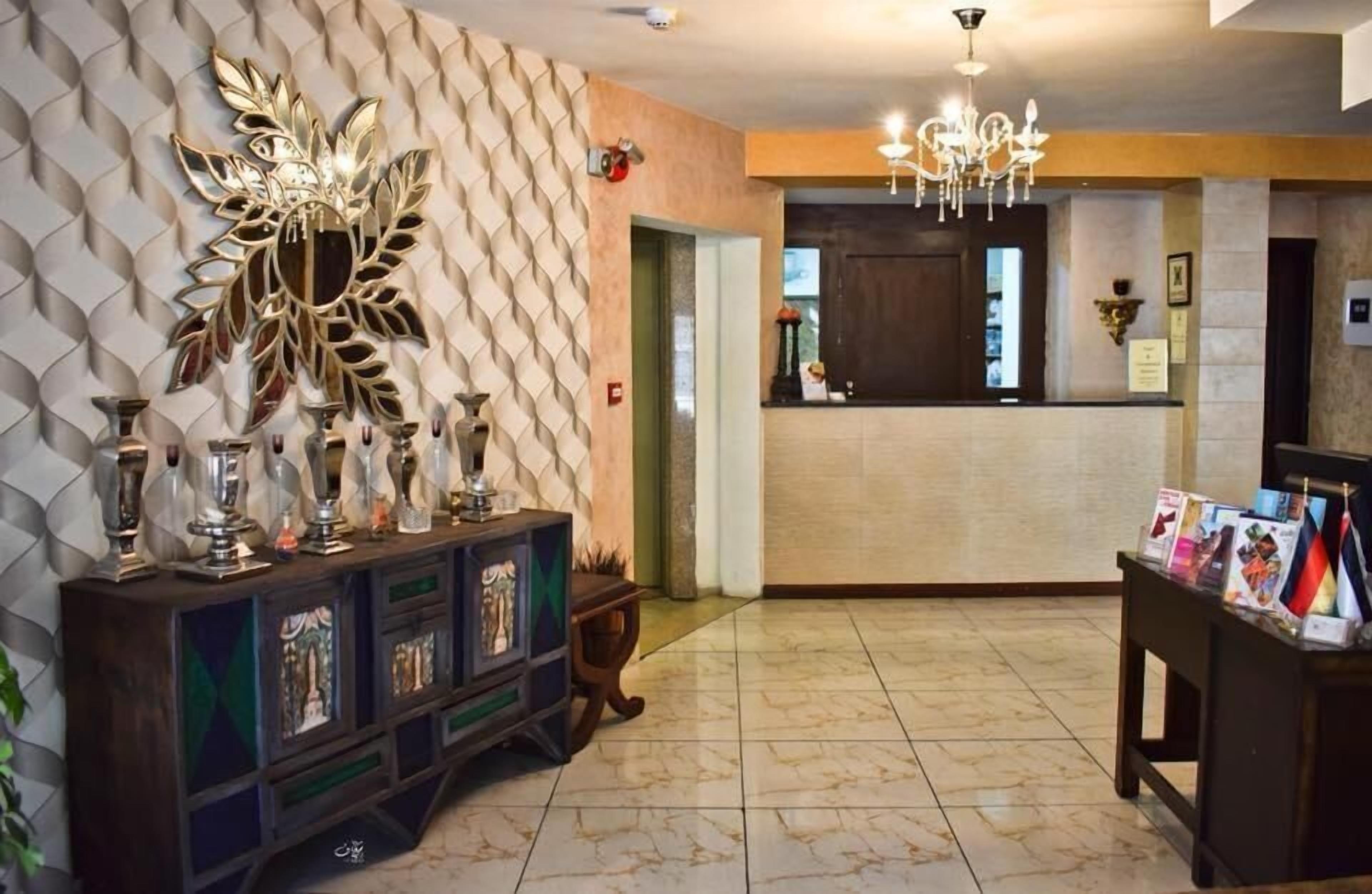 Un'area di accoglienza con una parete decorativa, una scrivania della reception e un lampadario.