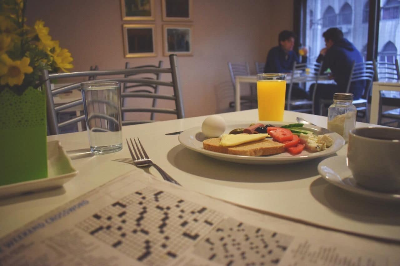 A breakfast setting with a plate of toast, eggs, tomatoes, and a glass of orange juice.