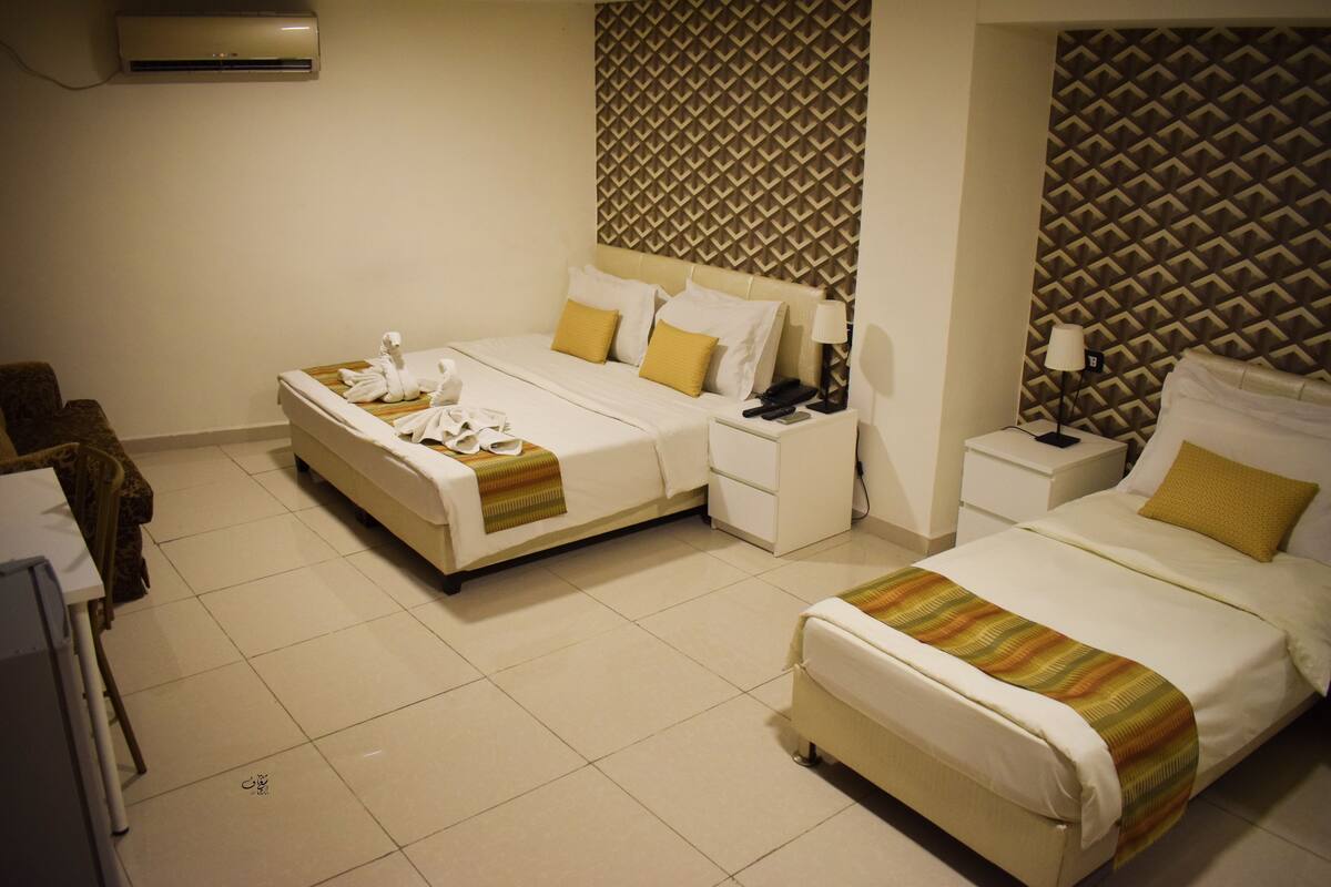 A hotel room with two beds, a desk, and a chair.