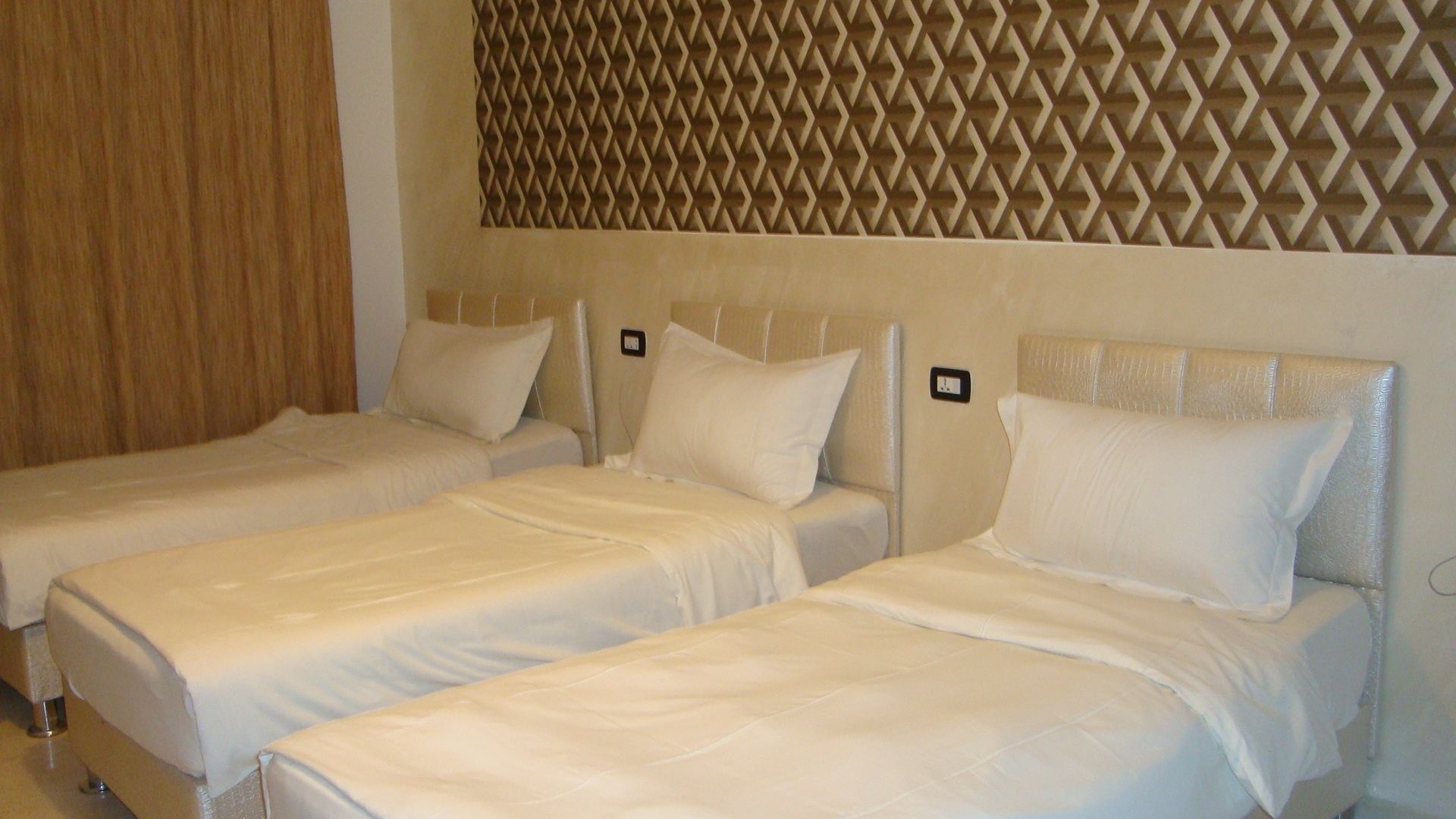 A hotel room with two single beds, each with a headboard and pillow.