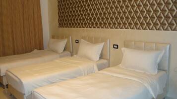 A hotel room with two single beds, each with a headboard and pillow.