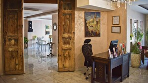 A lobby with wooden doors, a reception desk, a chandelier, and a painting on the wall. - Rafi Hotel Amman (Amman)