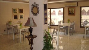 A spacious dining area with multiple tables and chairs, a decorative lamp, and framed artwork on the walls. - Rafi Hotel Amman (Amman)