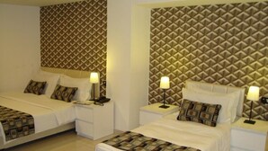 A hotel room with two beds, each with a patterned headboard, white bedding, and bedside lamps. - Rafi Hotel Amman (Amman)