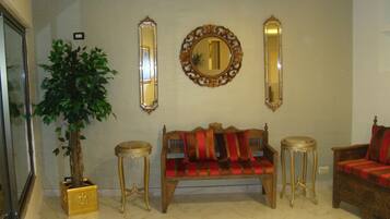 A living room with a sofa, two side tables, a potted plant, and three wall mirrors.