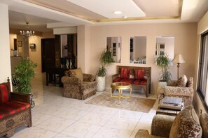 A spacious living room with a sofa set, a coffee table, and two potted plants.