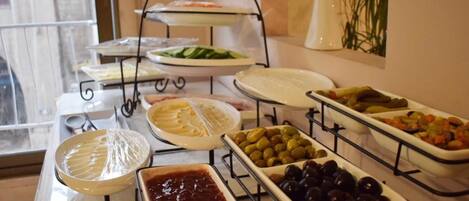 A buffet with various food items including olives, pickles, and sauces.