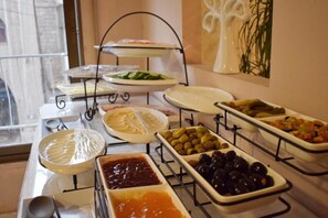 A buffet with various food items including olives, pickles, and sauces.