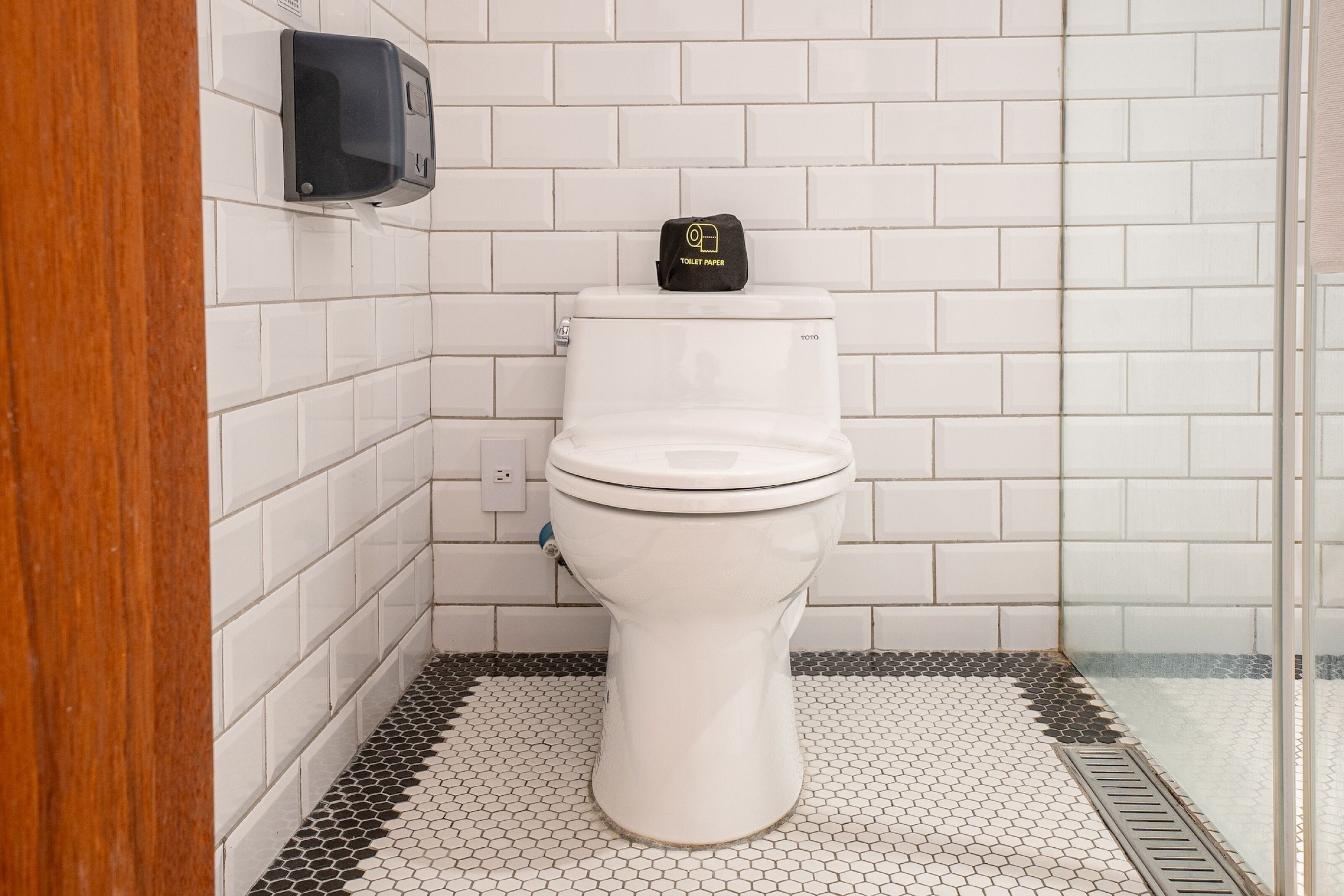 A white toilet with a black toilet paper holder on the wall.