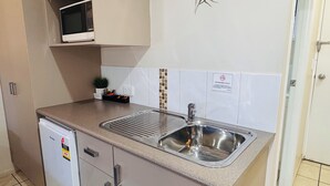 A kitchen with a stainless steel sink, a microwave, a small potted plant, and a 'No Smoking' sign.