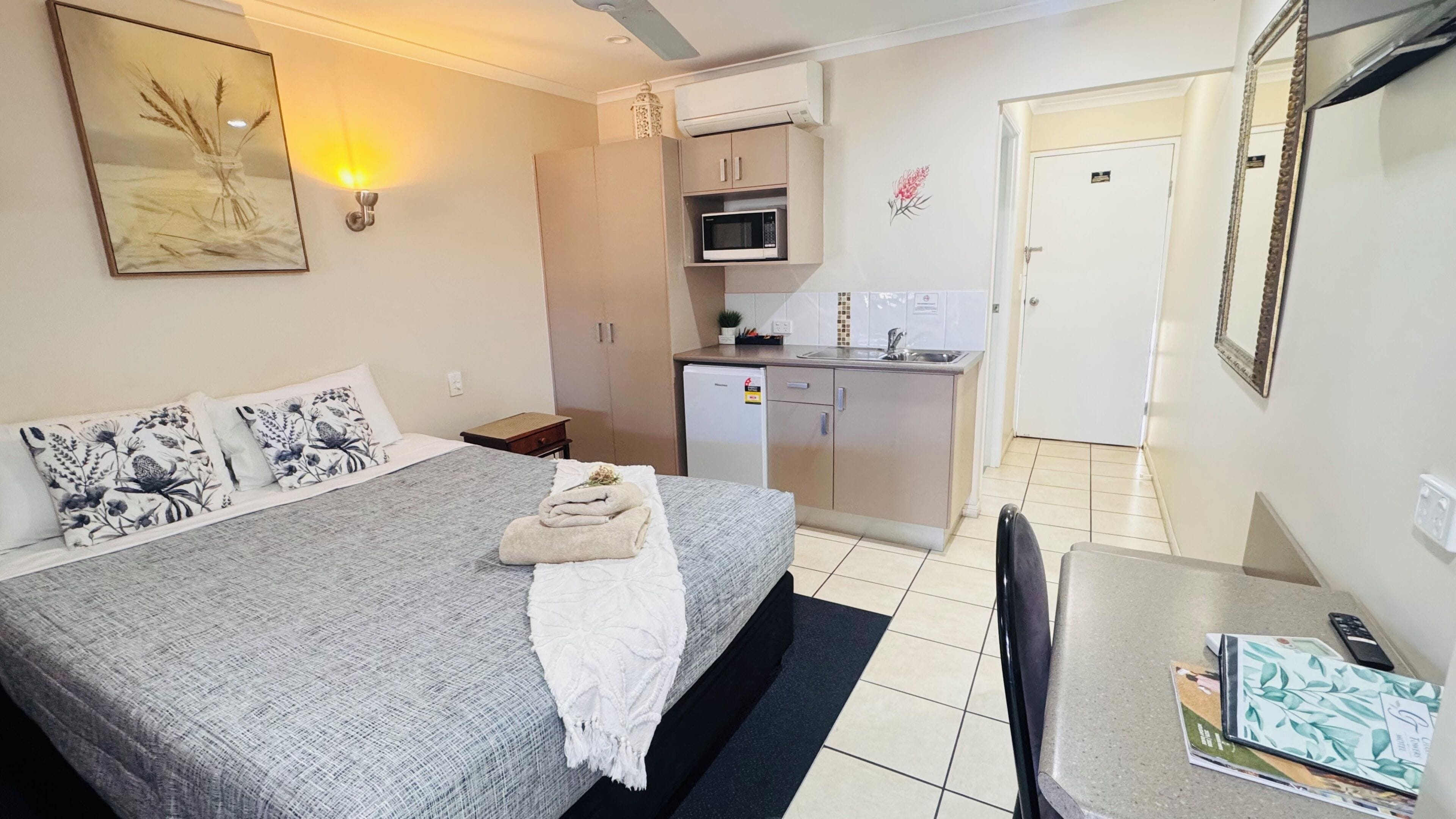 Una habitación de hotel con cama, kitchenette, escritorio y una silla.