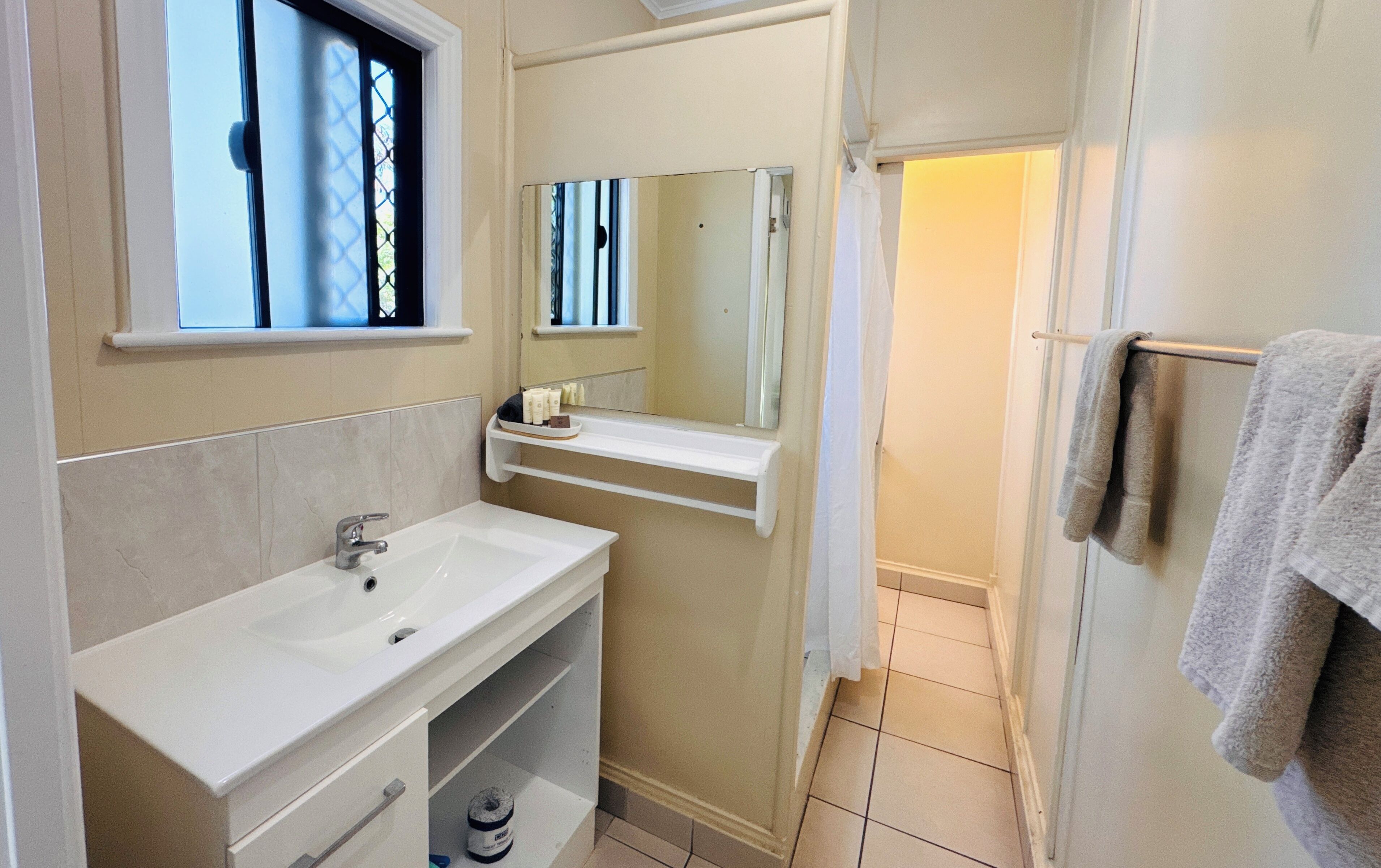 Un bagno con lavandino, specchio e portasciugamani.