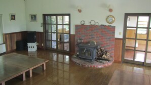 Un salón amplio con chimenea de ladrillo, suelo de madera y un gran ventanal corredera que da al exterior.