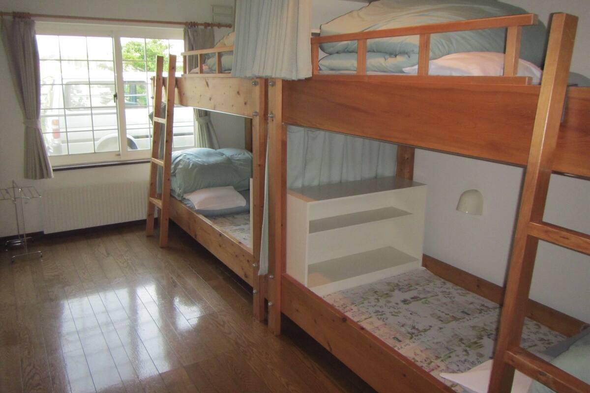 Habitación con literas, ventana, suelo de madera y radiador.