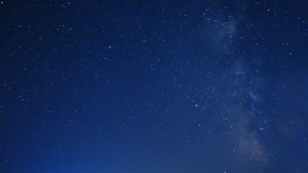 Una casa con múltiples ventanas y un alero visible, frente a un cielo nocturno estrellado.