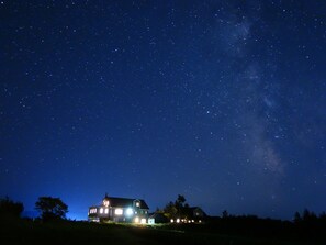 A house with multiple windows and a visible roofline, set against a starry night sky. - Kiyosato Ihatov Hostel (Kiyosato)