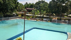 A large outdoor swimming pool surrounded by trees and buildings. - Amandari Cove (General Santos)