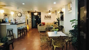Ein Restaurant mit Barbereich, Sitzgelegenheiten mit gemusterten Stühlen und einem gefliesten Boden.