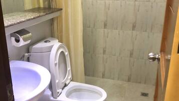 A bathroom with a toilet, sink, and shower curtain.
