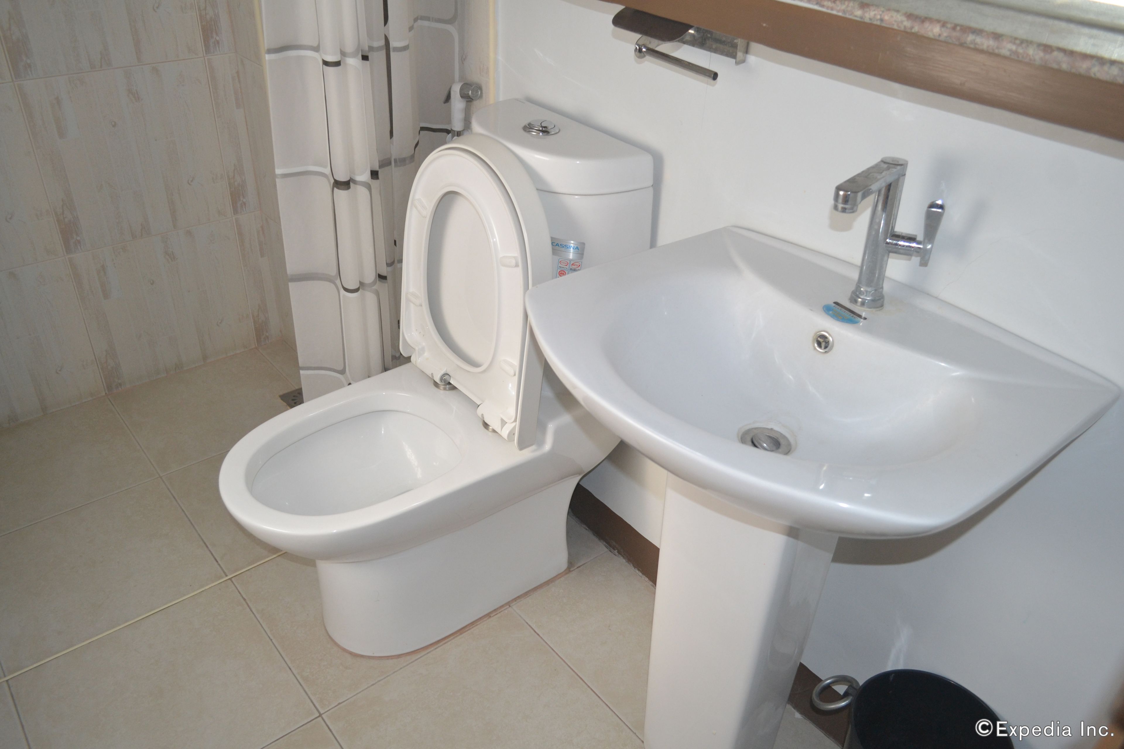 A bathroom with a toilet, sink, and tiled floor.