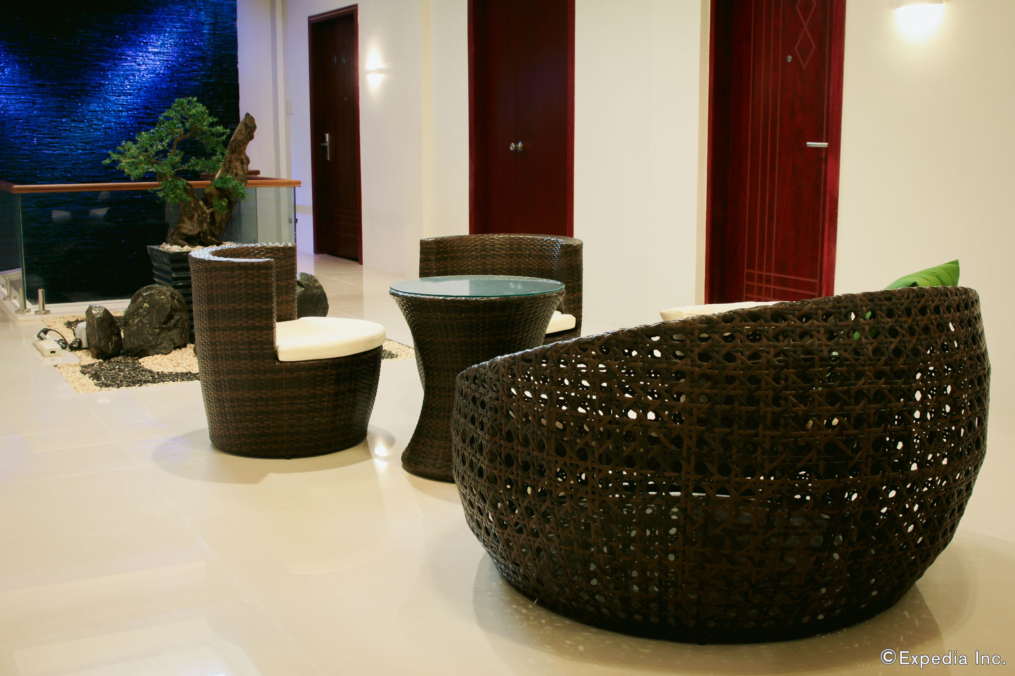 Eine moderne Lobby mit Korbmöbeln, einem Glastisch und einem Bonsai-Baum.