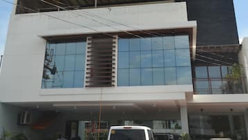 Un edificio moderno con una grande facciata in vetro, una terrazza sul tetto e un cartello con scritto