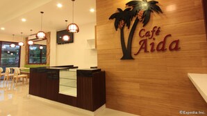 Un comptoir d’accueil avec un mur en bois et une enseigne sur laquelle on peut lire « Café Aida ».