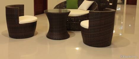A modern lobby with wicker furniture, a glass coffee table, and a view of the outside.