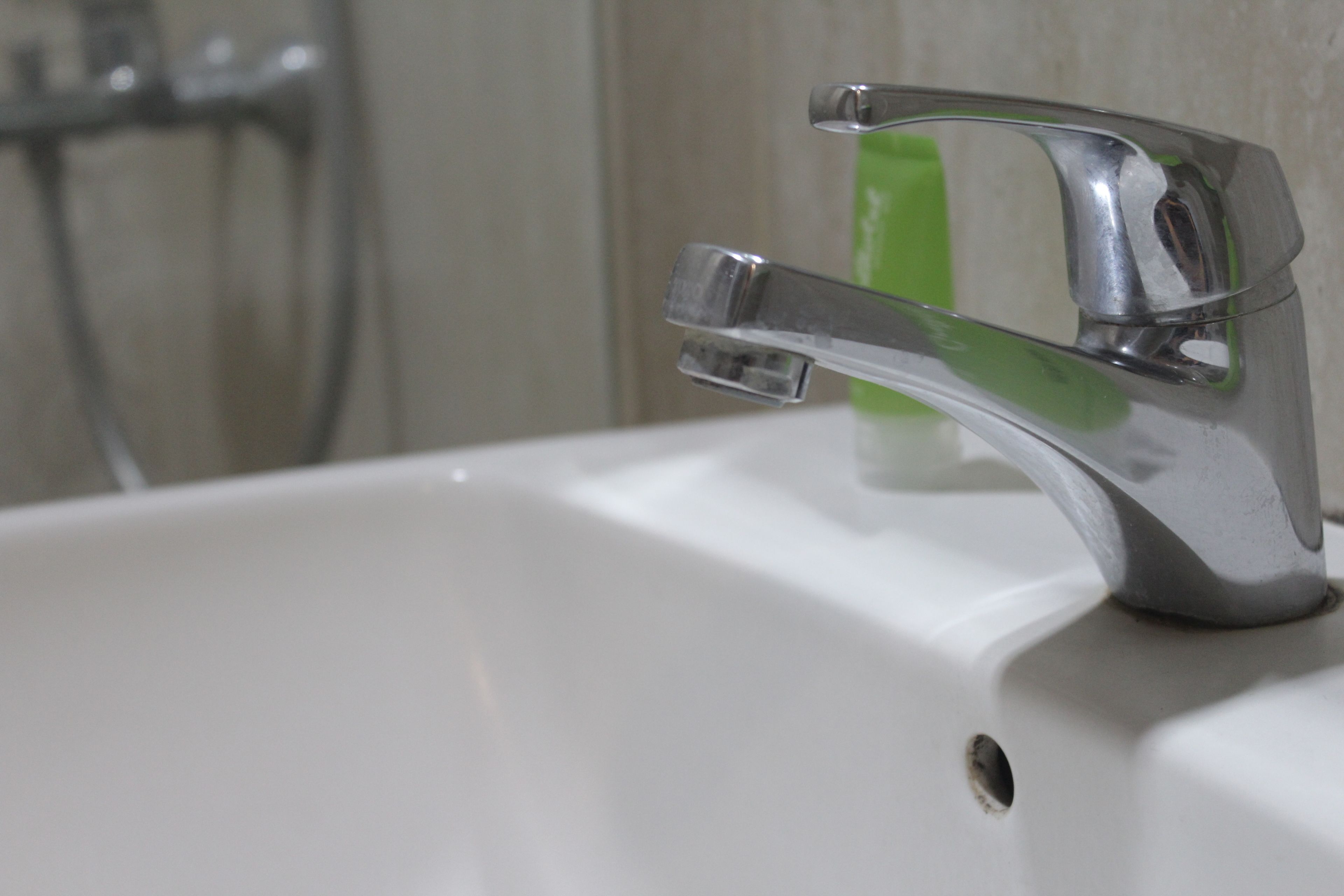 A bathroom sink with a chrome faucet and a green soap dispenser.