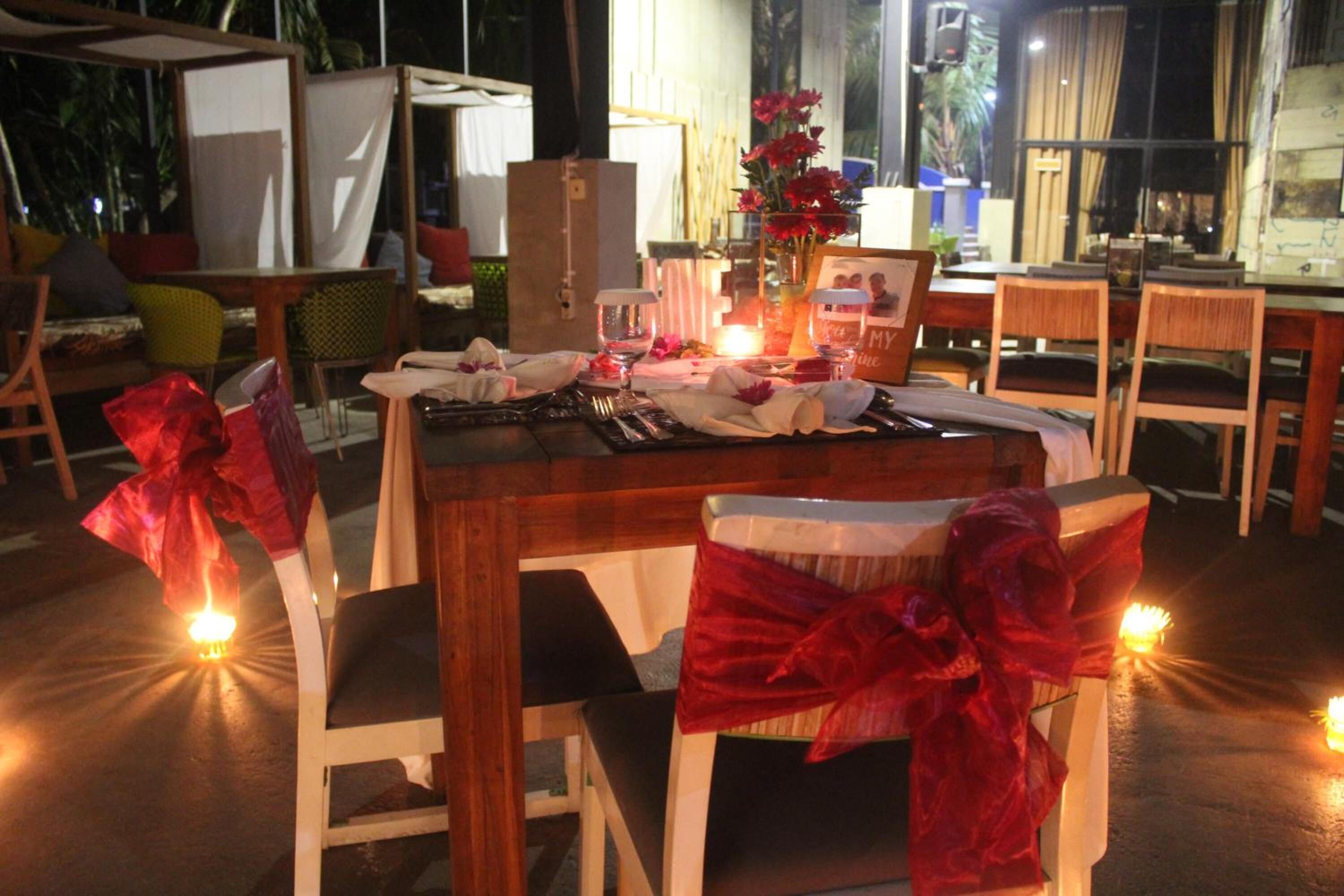 A dining table set with chairs, candles, and a vase of flowers.