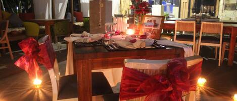 A dining table set with chairs, candles, and a vase of flowers.