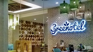 A Greenotel with a modern interior, including a wall of circular mirrors and a neon sign. - Greenotel Cilegon (Cilegon)