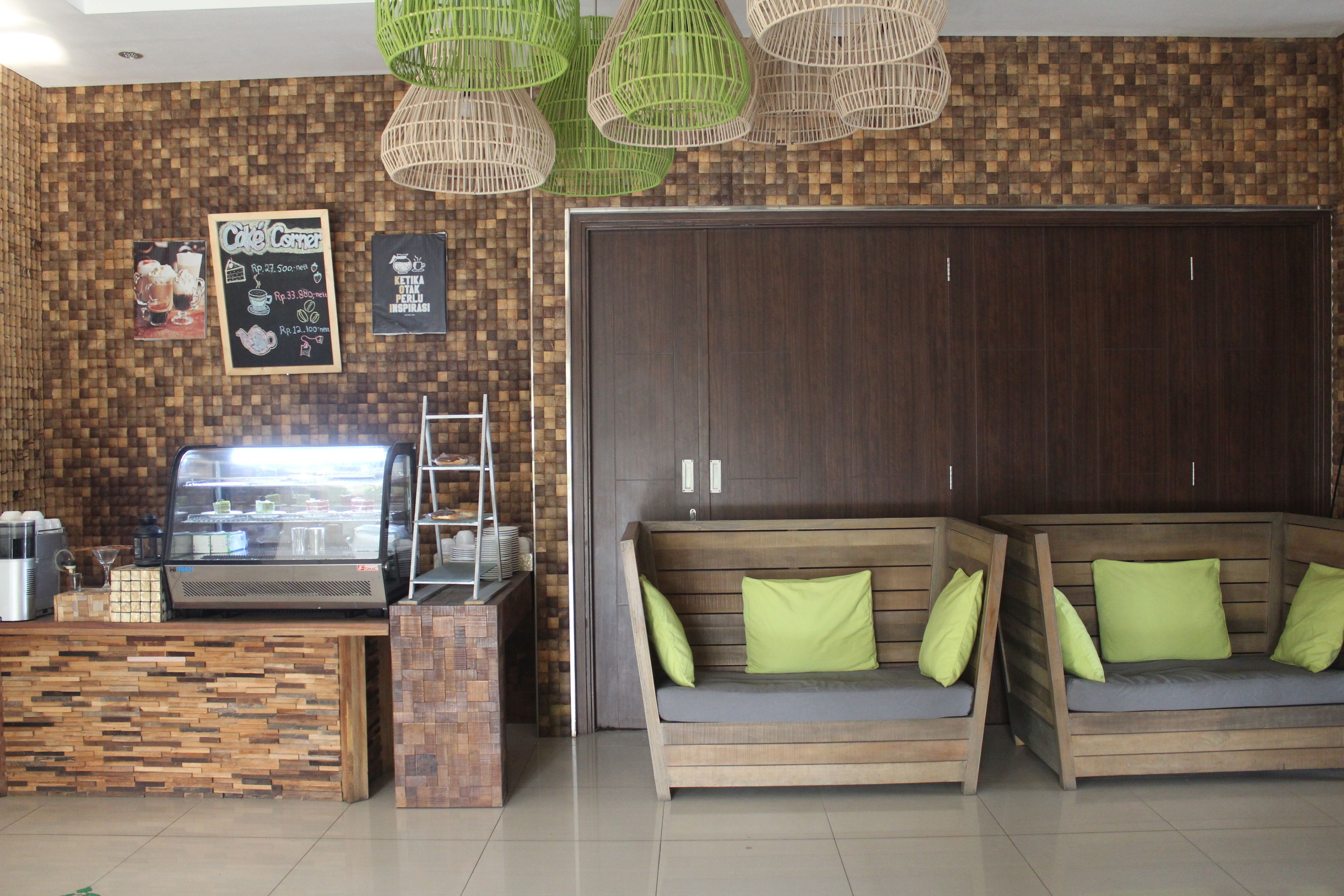 A modern interior with a wooden reception desk, a glass display case, and a wooden sofa with green cushions.