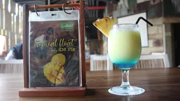 Ein tropisch dekoriertes Getränk mit Ananas-Garnitur und einem Schild für 'Greenhotel', das ein tropisches Floßgetränk und einen Preis von 35.000 IDR zeigt.