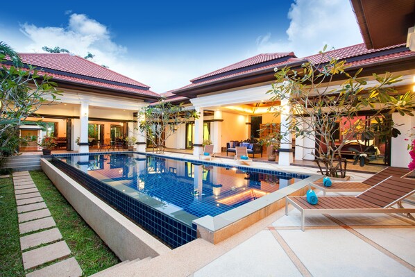 A modern house with a swimming pool, outdoor seating, and a well-maintained garden. - Jewels Villas Phuket (Si Sunthon)