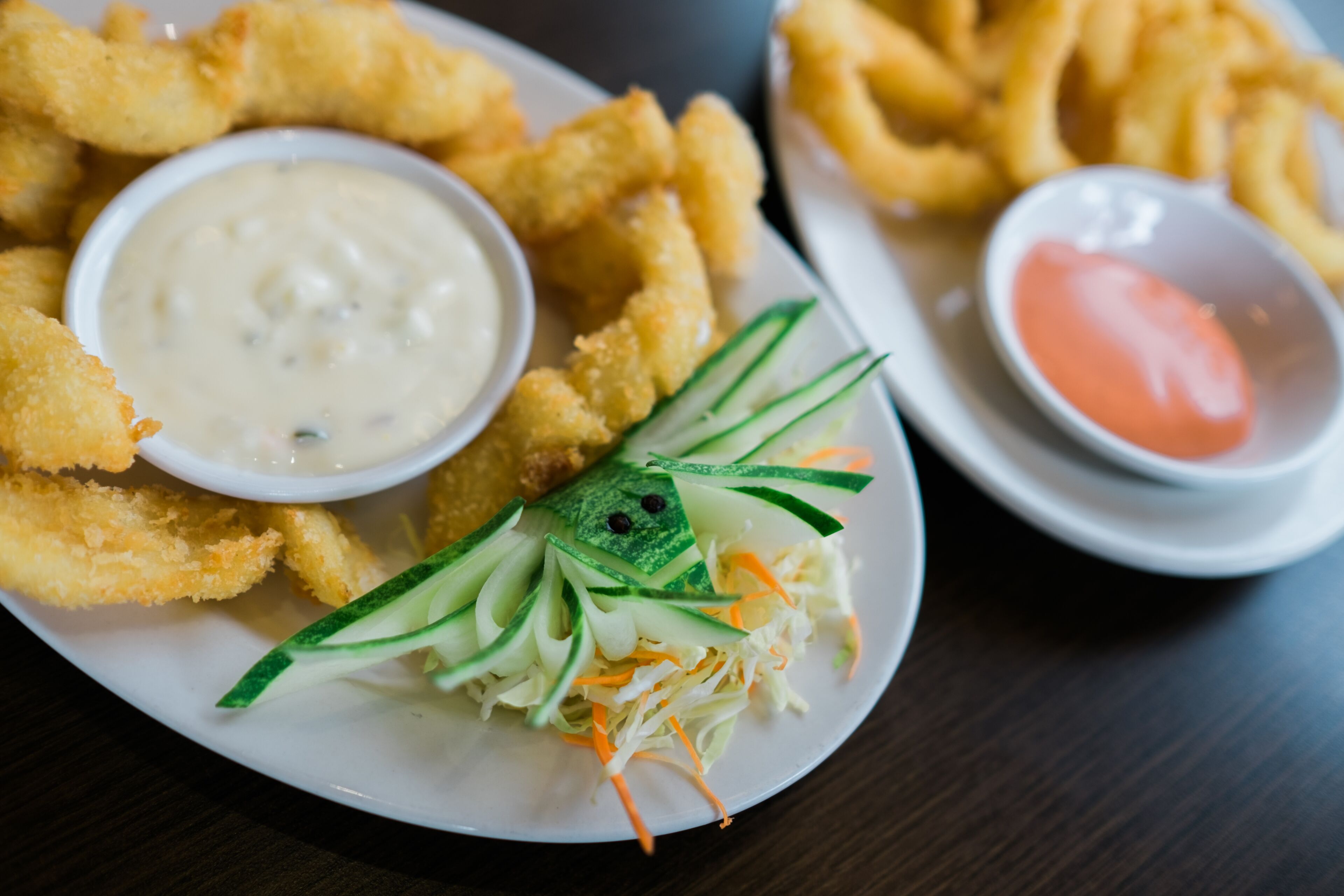 A plate of fried food with two dipping sauces and a side salad.