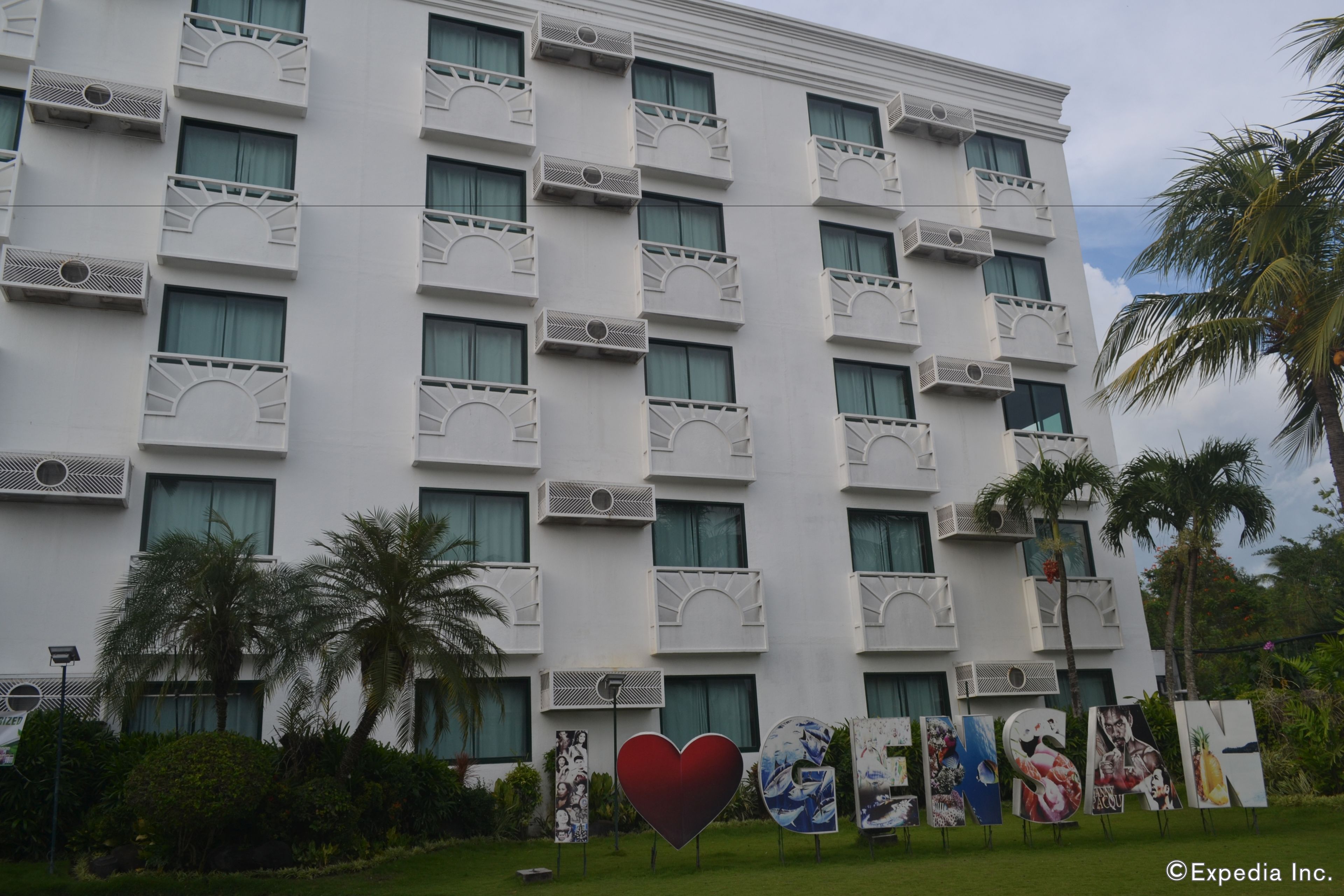 Ein mehrstöckiges Hotel mit Balkonen und Klimaanlagen, im Vordergrund ein Schild mit dem Wort 'RESORT'.