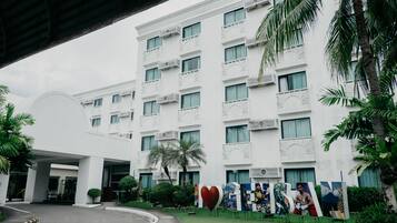 A multi-story hotel with a white facade, balconies, and a covered entrance.