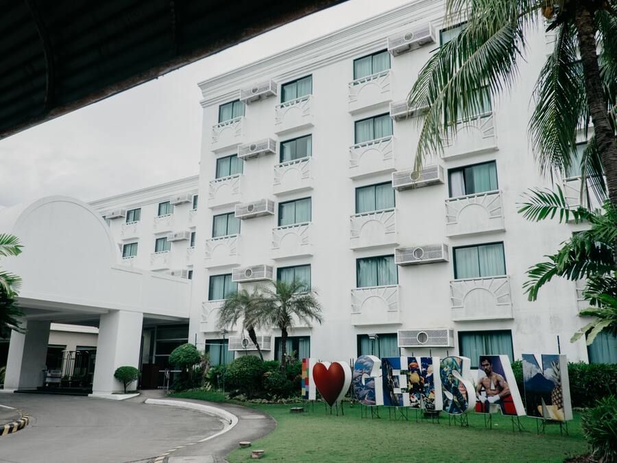 A multi-story hotel with a white facade, balconies, and a covered entrance.