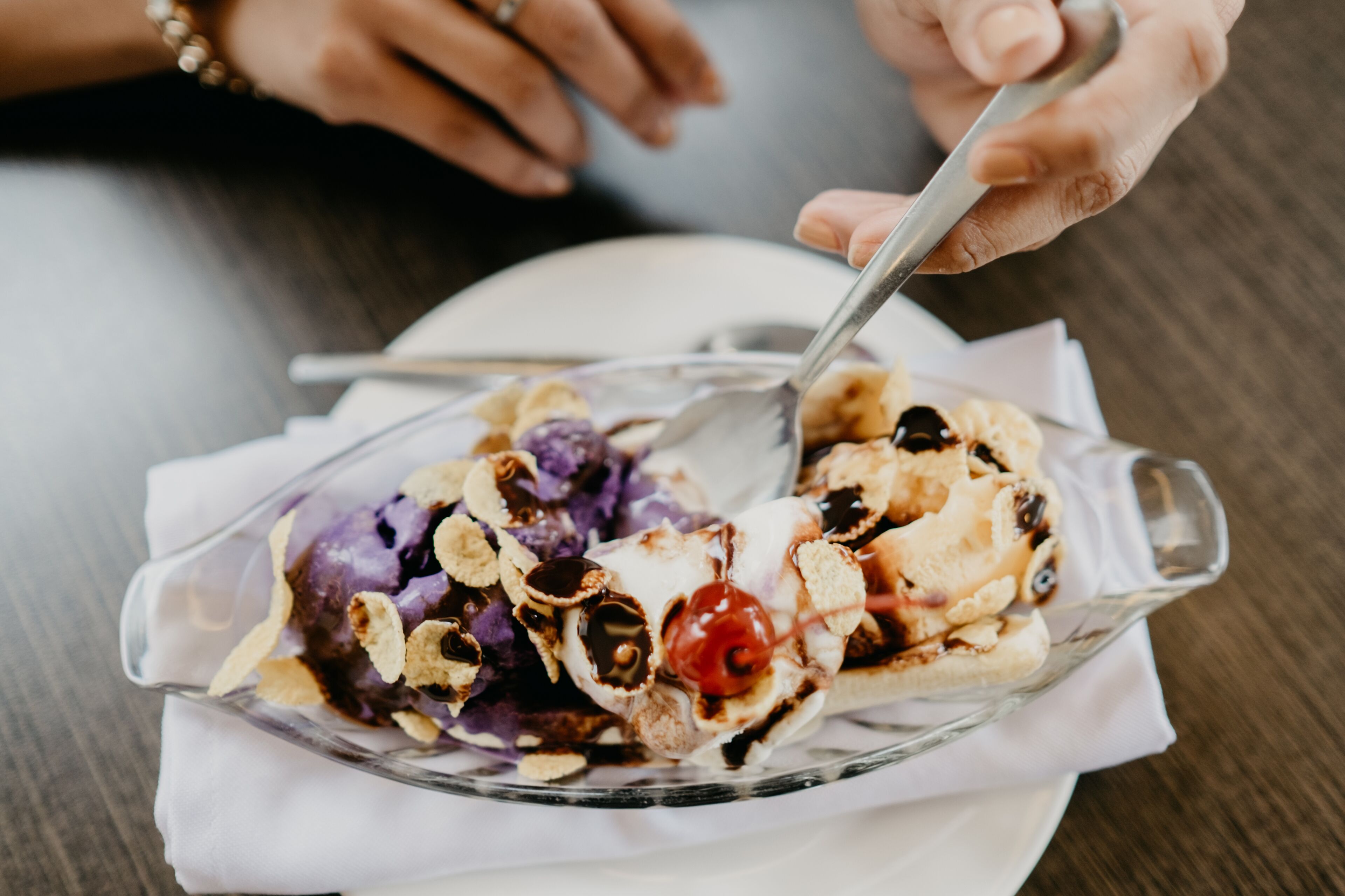 A dessert in a clear glass dish with a spoon, placed on a white napkin.