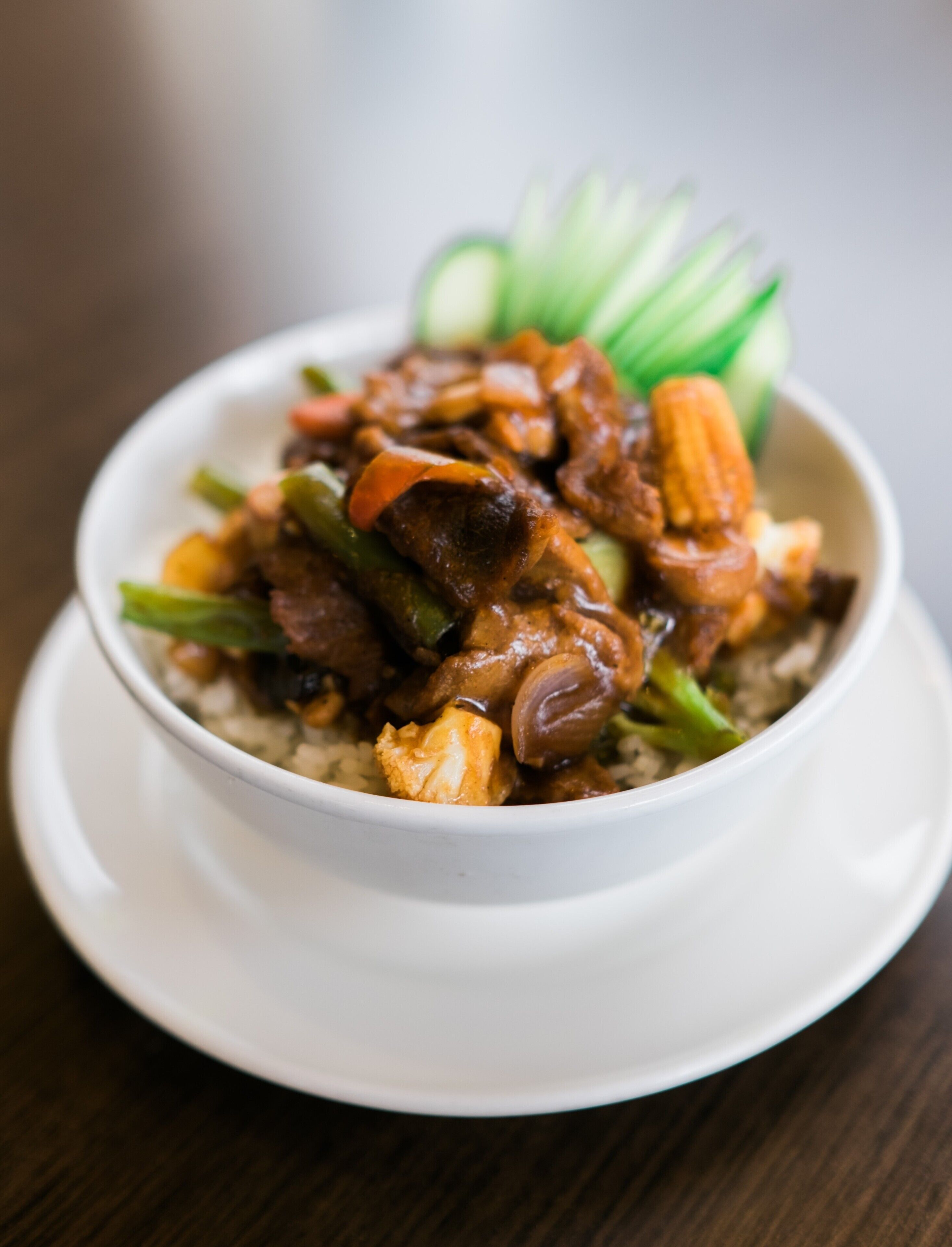 A bowl of food with various ingredients, including meat and vegetables, served on a white plate.