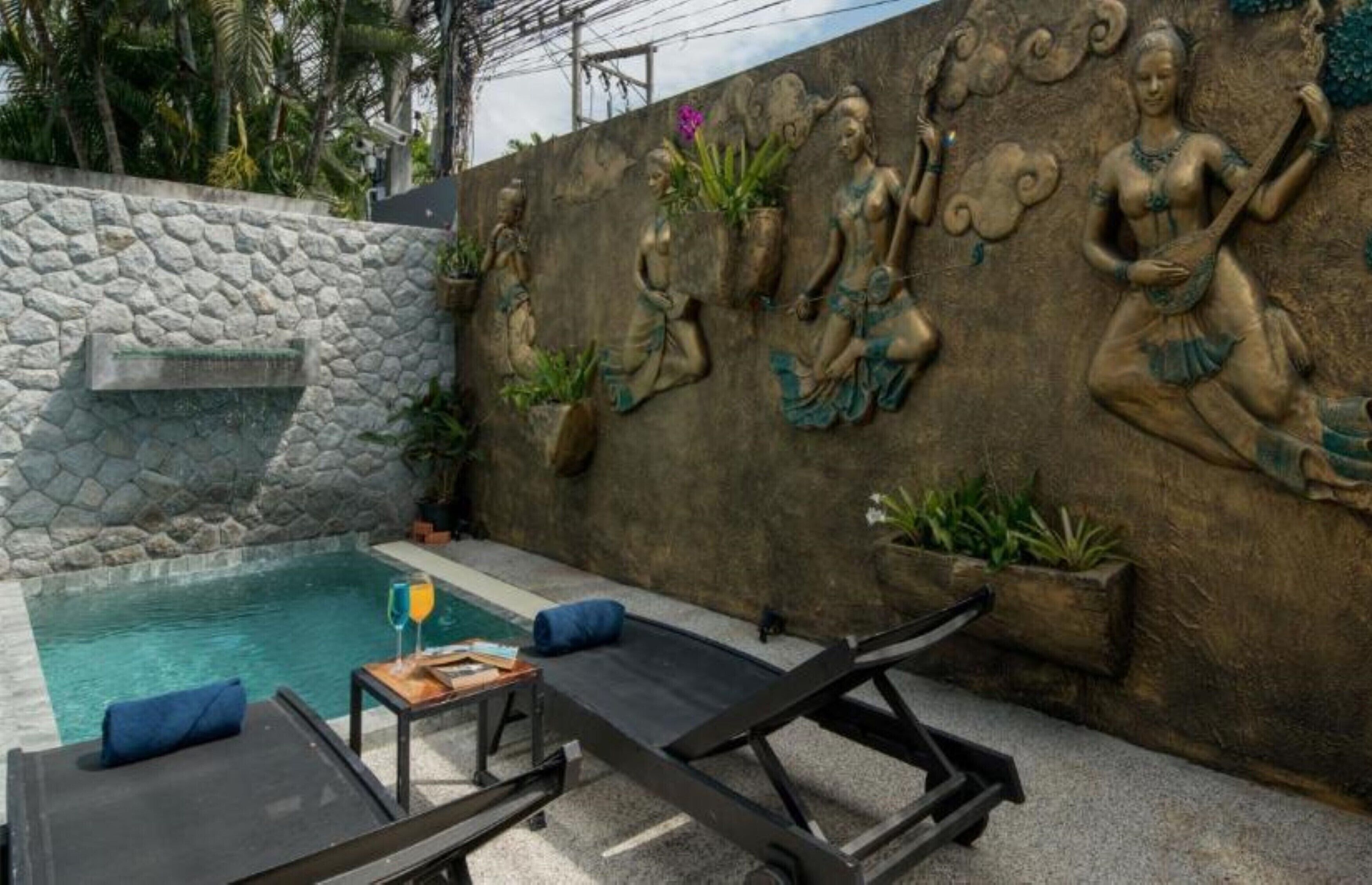Un espace piscine agrémenté de murs en pierre, de chaises longues et d’œuvres d’art décoratives.