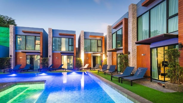A modern hotel with a swimming pool, lounge chairs, and a well-maintained lawn.