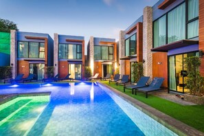 A modern hotel with a swimming pool, lounge chairs, and a well-maintained lawn. - Peace Blue Naiharn Naturist Resort Phuket (Rawai)