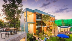 A modern building with a courtyard, outdoor seating, and a green netted area.