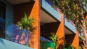 A modern building with multiple balconies, large windows, and potted plants.