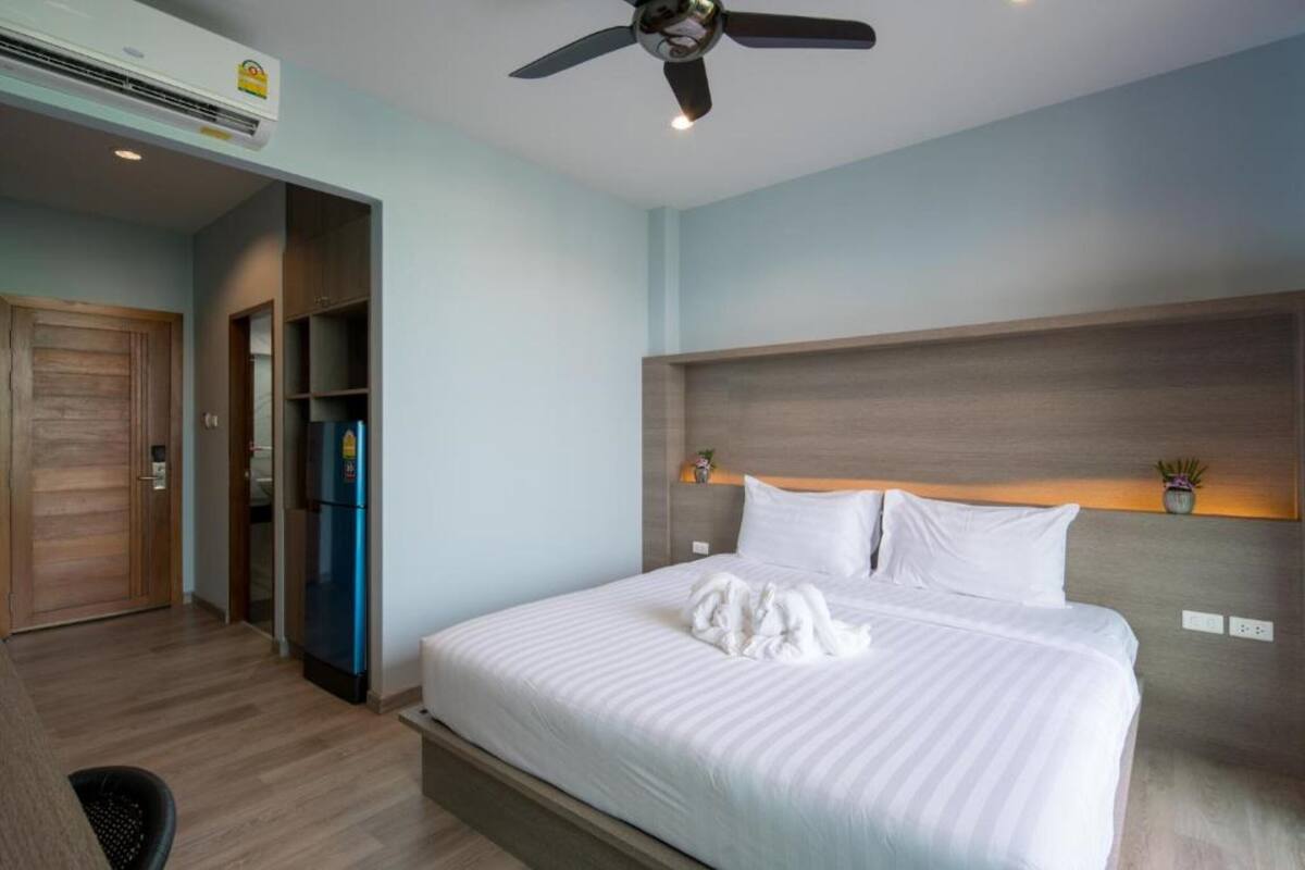 Ein Hotelzimmer mit Bett, Deckenventilator, integriertem Kleiderschrank und Kühlschrank.