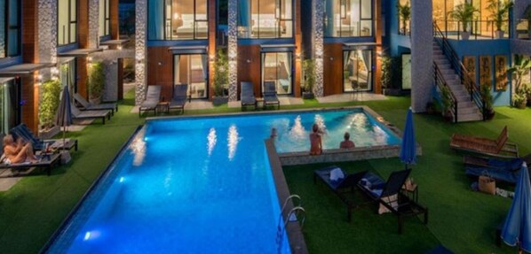 Ein modernes Hotel mit großem Hallenbad, Liegestühlen und einem gepflegten Rasen.