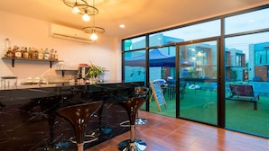 A modern kitchen with a large island, bar stools, and a view of the outdoor pool area.