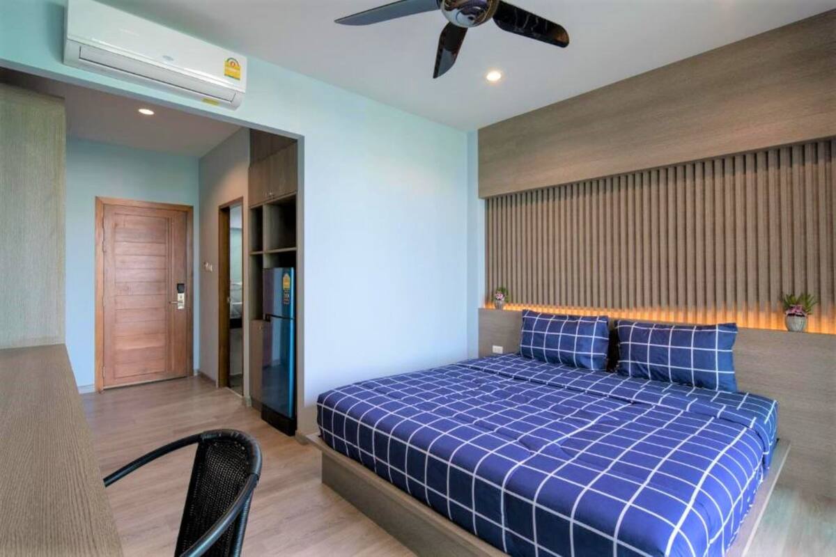 Ein Hotelzimmer mit einem Bett, einem Deckenventilator, einer Holztür und einer kleinen Sitzecke.
